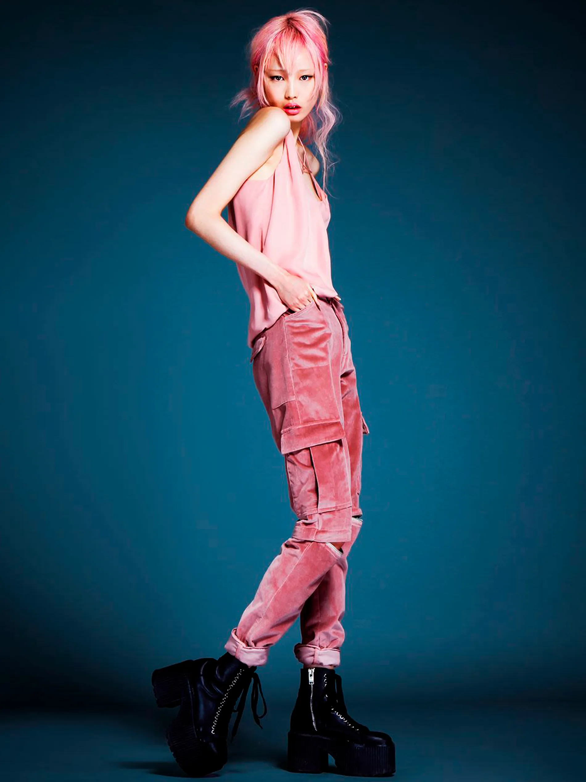 Fernanda Ly with pink hair in a pink Dane tank and pink velvet Rolf cargo pants against a teal backdrop